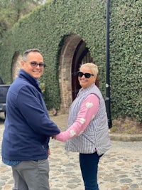 a man and woman shaking hands in front of a cobblestone driveway