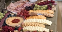 a platter of fruit, cheese and crackers on a table