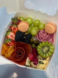 a box filled with fruit, meat, and macarons