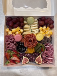 a white box filled with a variety of meats and cheeses